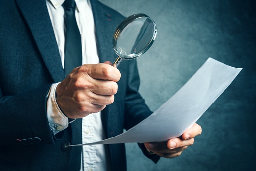 Tax inspector investigating financial documents through magnifying glass
